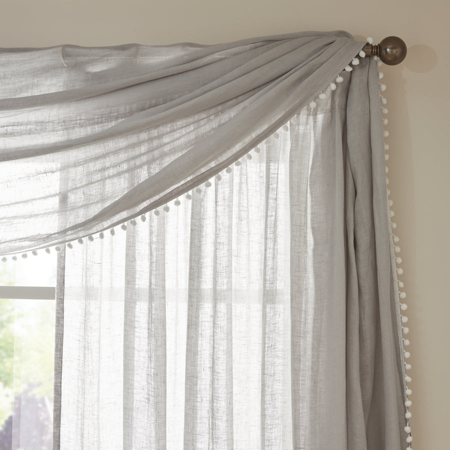 Light gray sheer linen curtains with decorative pom-pom trim