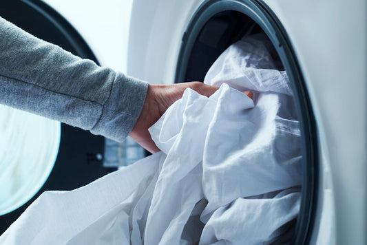 A person loading linen to a washing machine