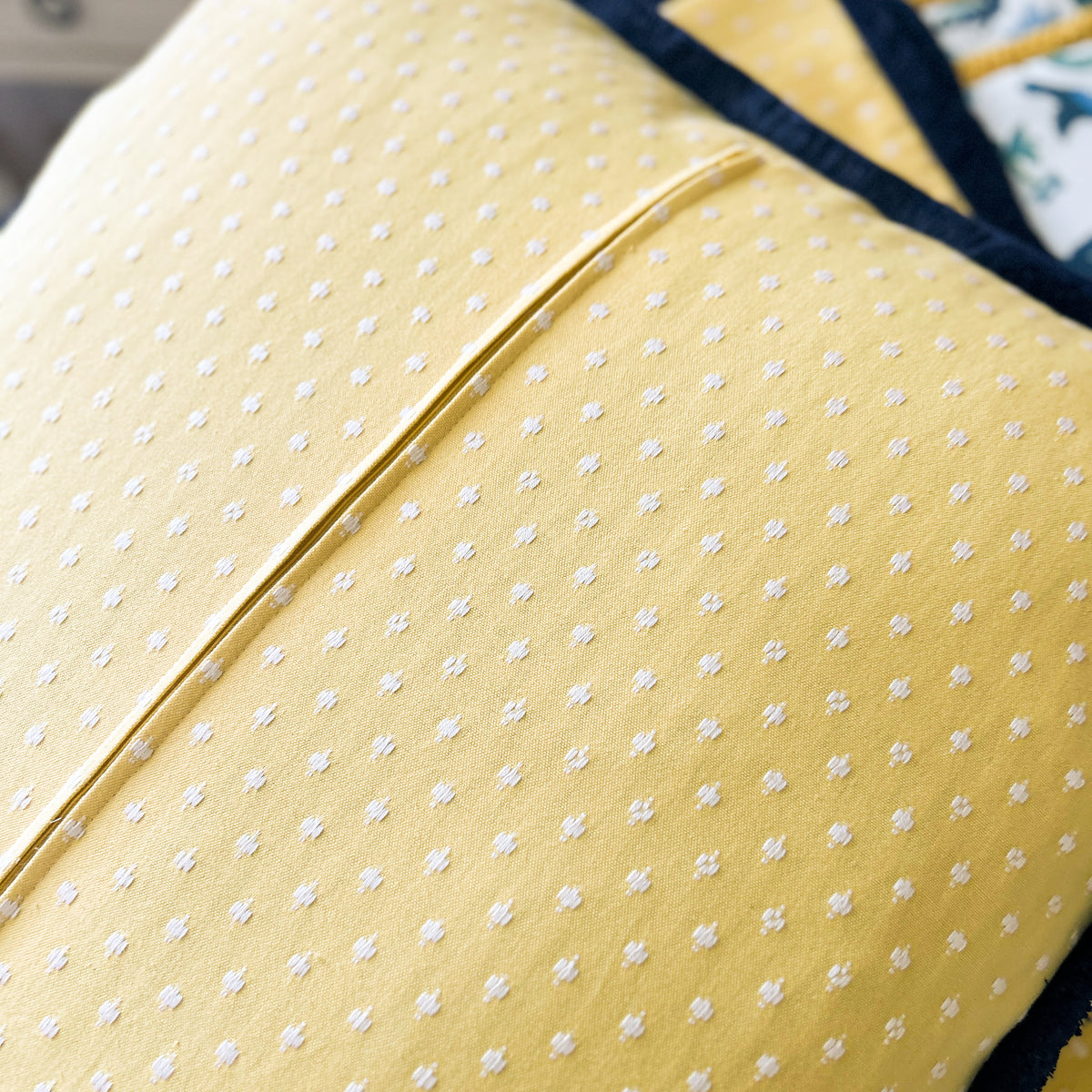 Close-up of a yellow polka dot fabric with a blue border.