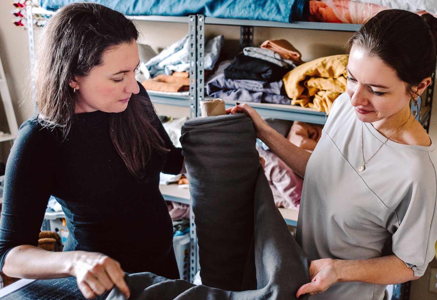 Two women working with fabric in a workshop setting.