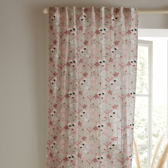 Floral patterned curtain hanging in front of a window with a neutral wall background