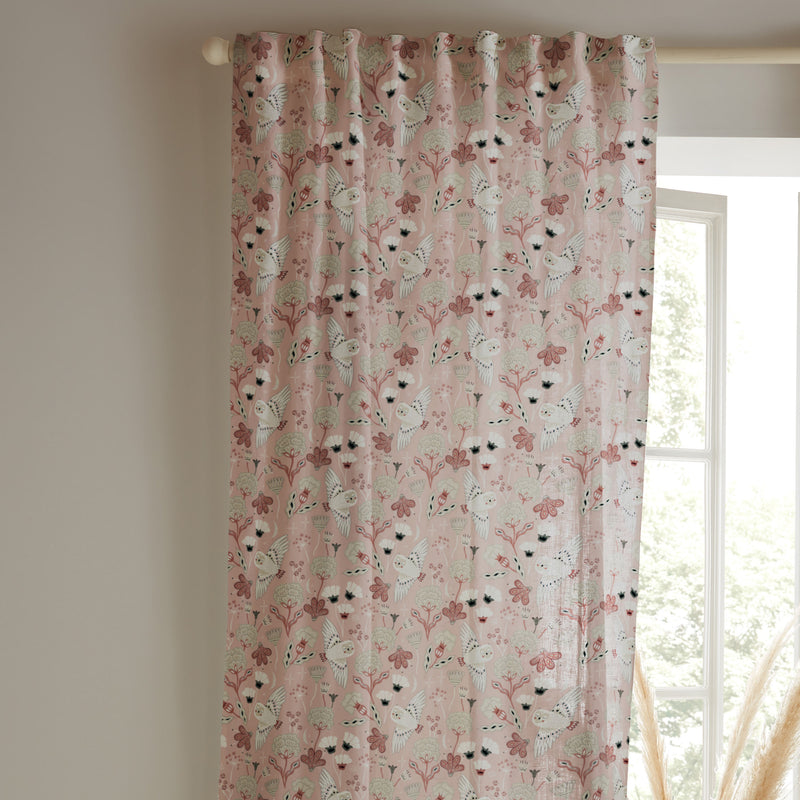 Floral patterned curtain hanging in front of a window with a neutral wall background
