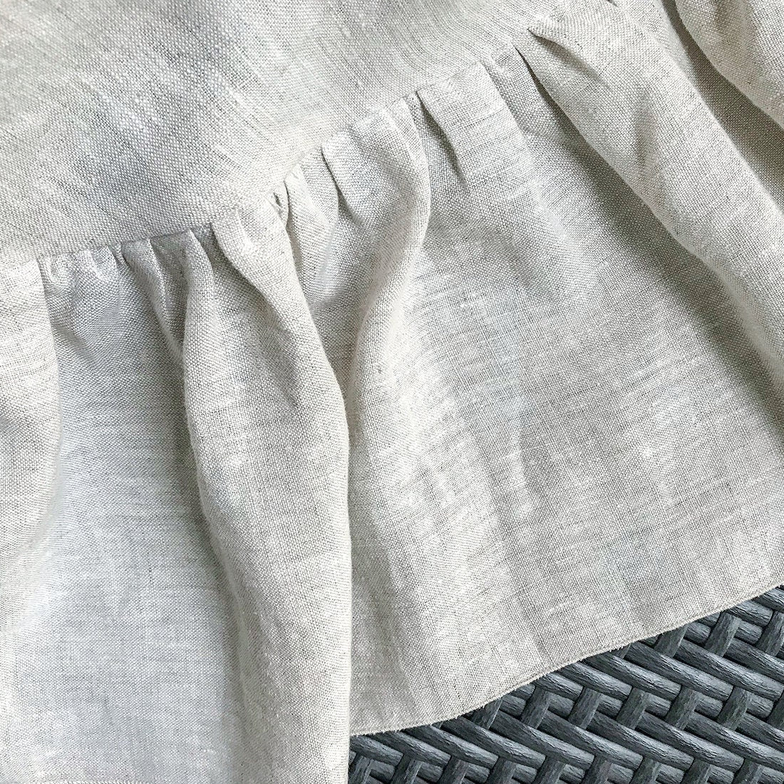 Close-up of a light gray textured fabric with a subtle pattern on a textured surface.