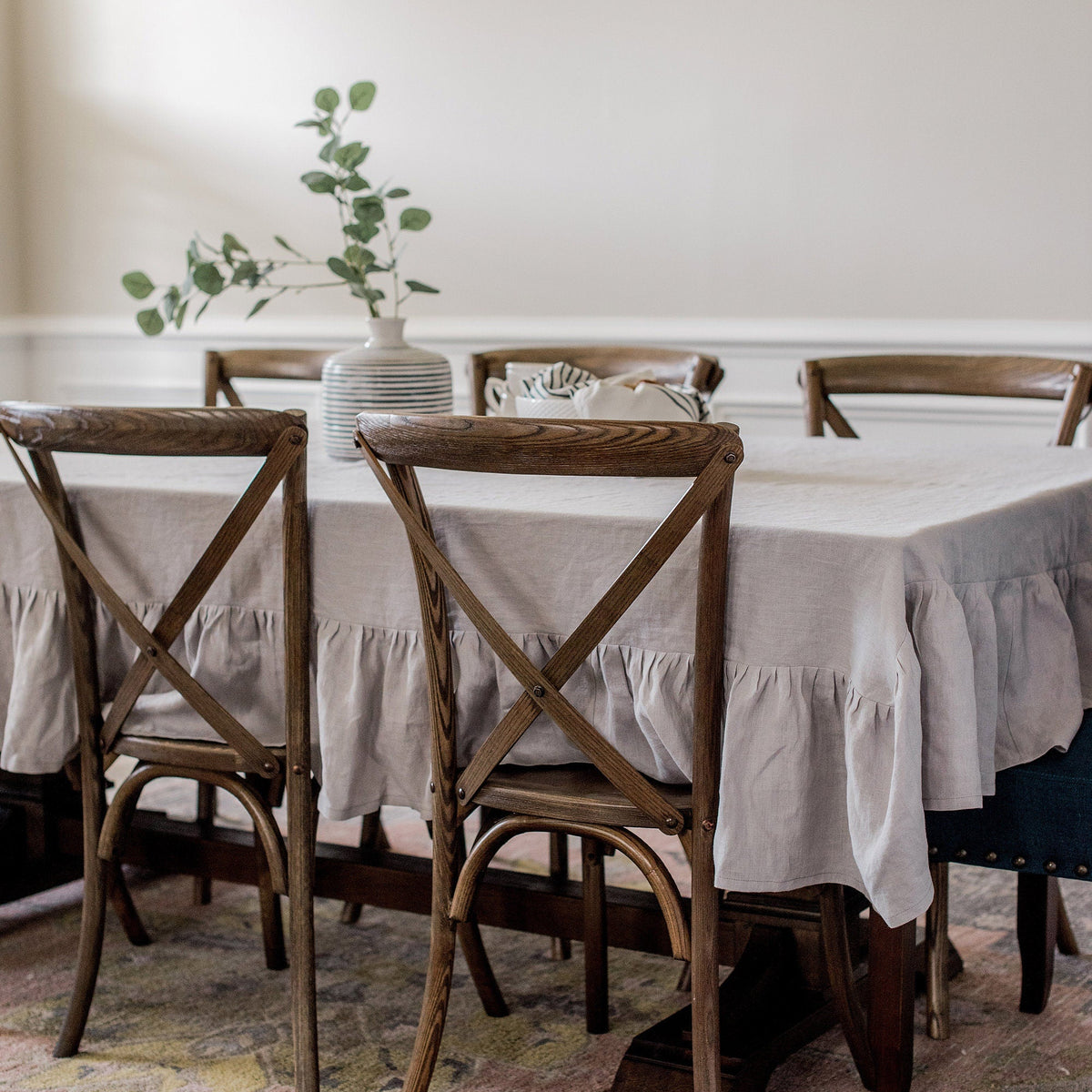Dining room with wooden chairs and a table covered with a white tablecloth.
