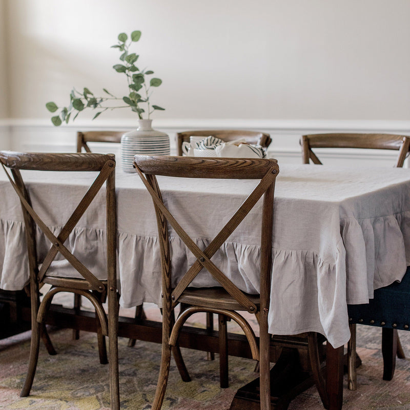 Dining room with wooden chairs and a table covered with a white tablecloth.