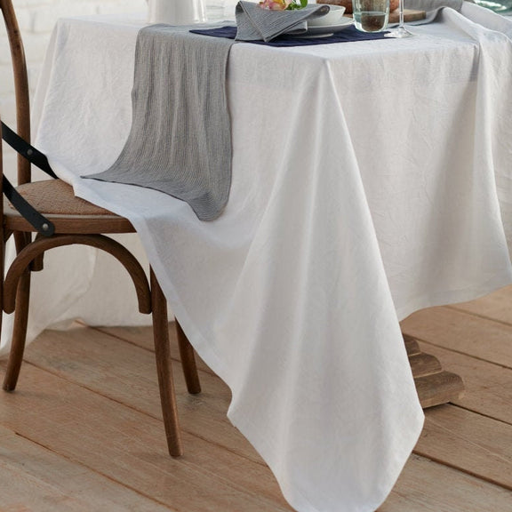 Dining table with a white tablecloth, wooden chair, and decorative items.