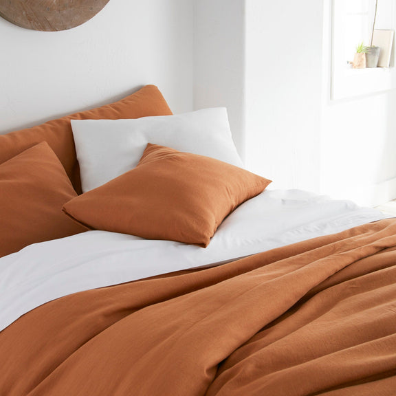 Bed with brown bedding and pillows in a bright room.