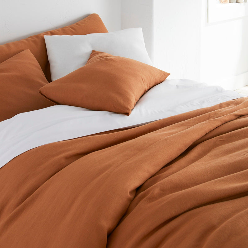 Bed with brown bedding and pillows in a bright room.