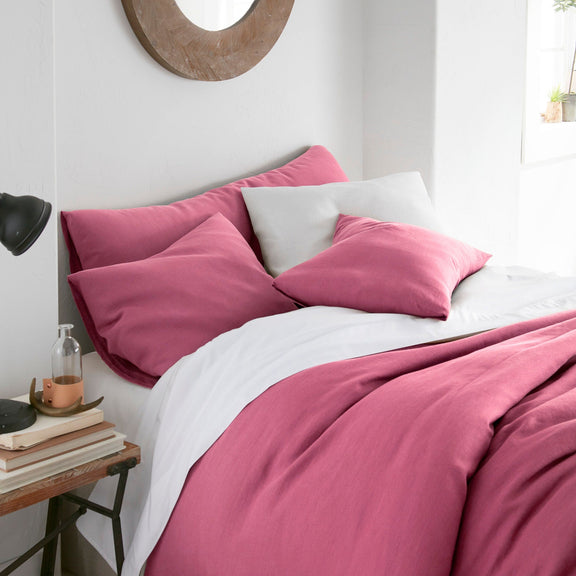 Bed with pink bedding and white pillows in a bedroom setting.