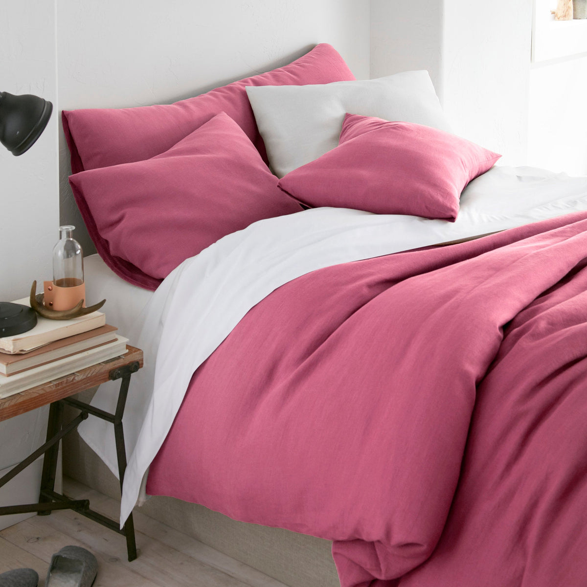 Bed with pink bedding and white pillows in a bedroom setting.