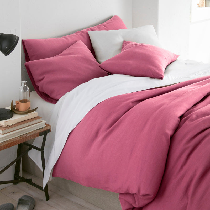 Bed with pink bedding and white pillows in a bedroom setting.