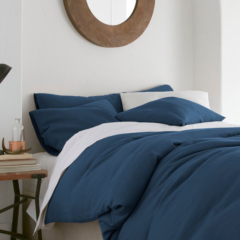 Bed with blue bedding and white pillows in a bedroom setting.