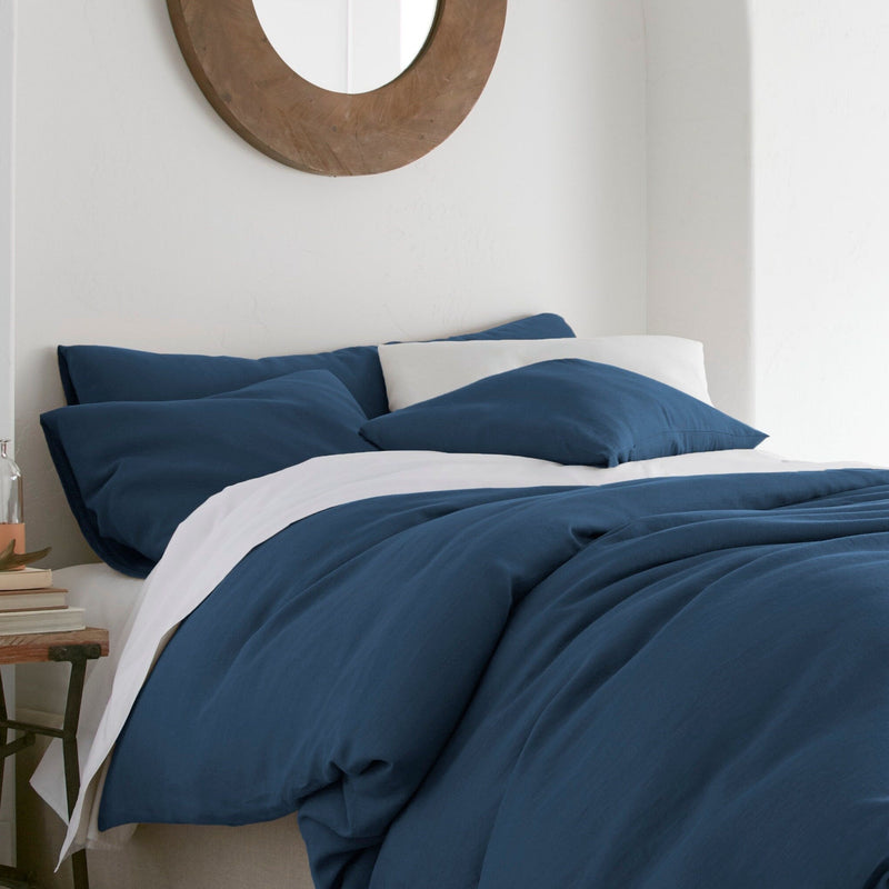 Bed with blue bedding and white pillows in a bedroom setting.