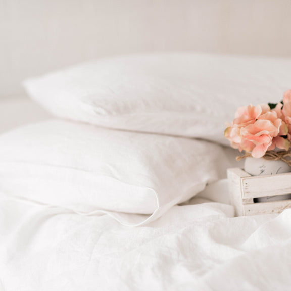 White bedding with pink flowers on a wooden crate