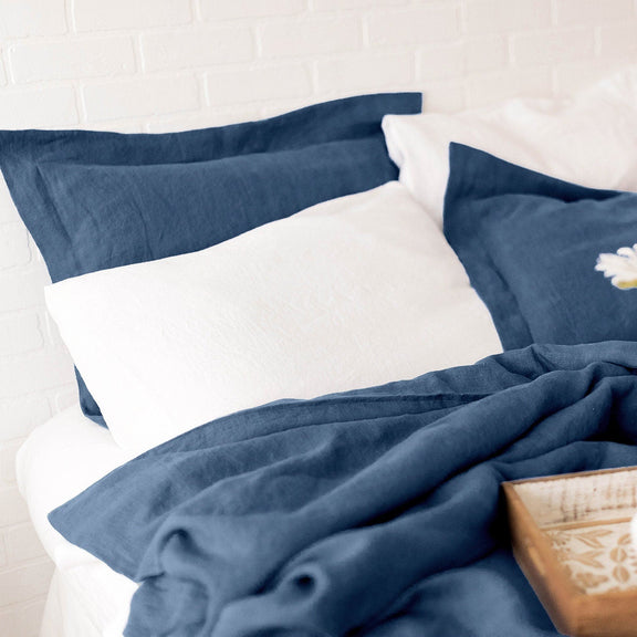 Blue and white bedding set with a vase of flowers on a tray.