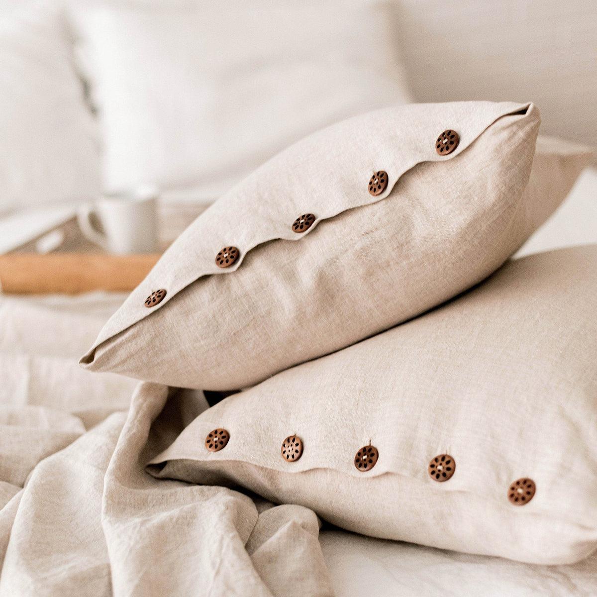 Beige pillows with button details on a bed with linen duvet