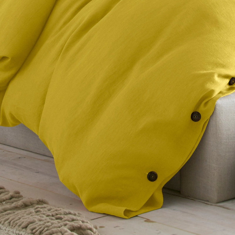 Yellow blanket draped over a beige sofa on a wooden floor.