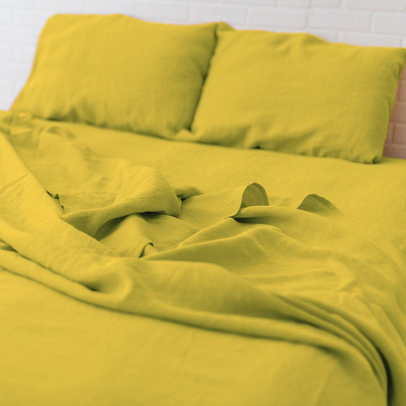 Yellow bedding set on a bed with a white wall background