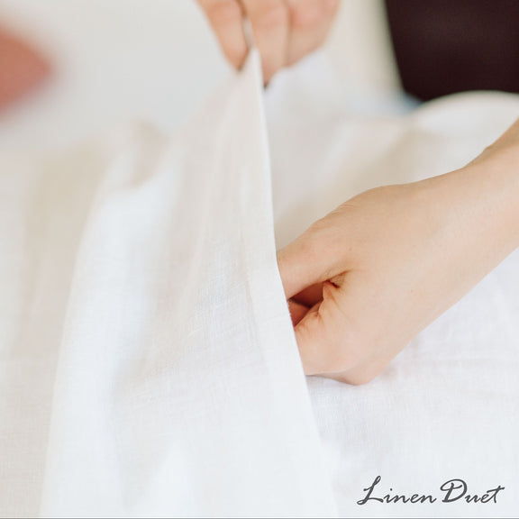 Close-up of hands holding a white linen drape.
