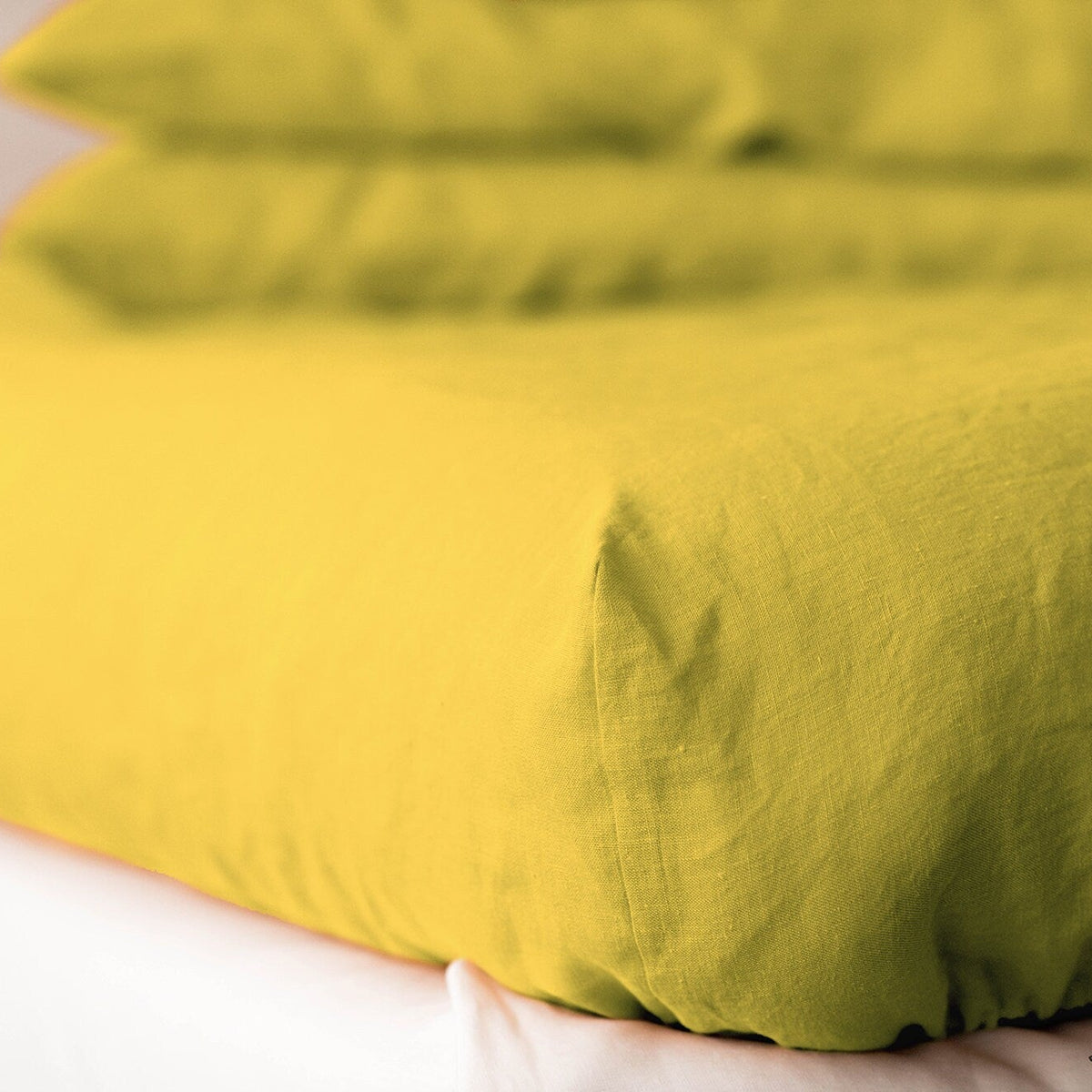 Yellow linen duvet on a bed with a neutral background