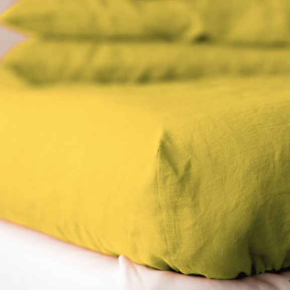 Yellow linen duvet on a bed with a neutral background