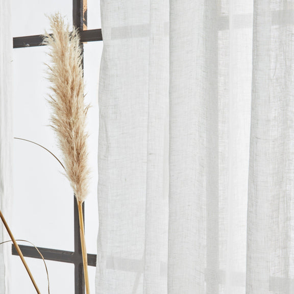 Sheer white curtain with a decorative plant against a light background