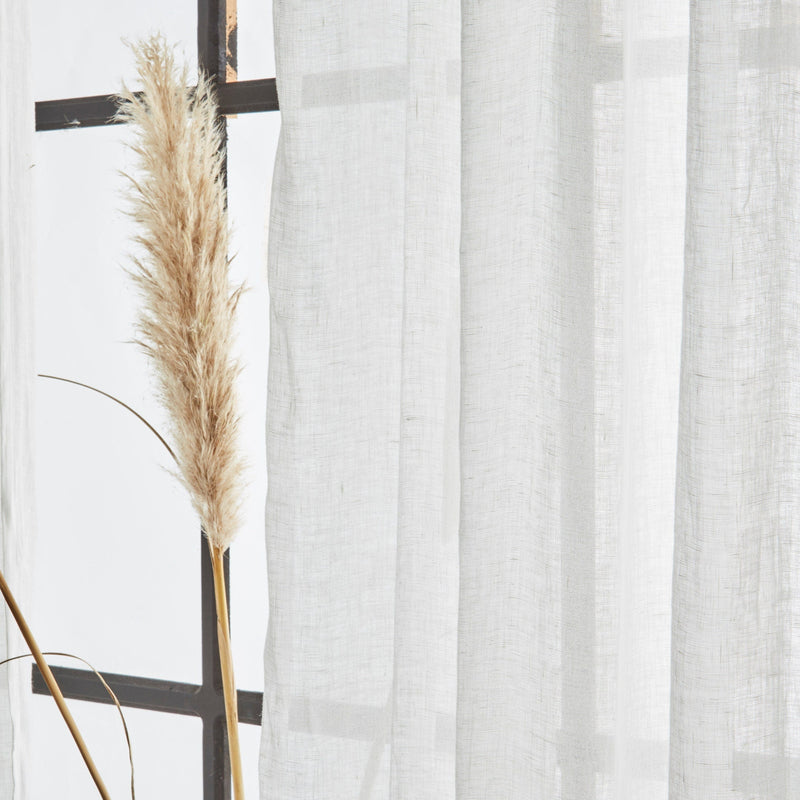 Sheer white curtain with a decorative plant against a light background