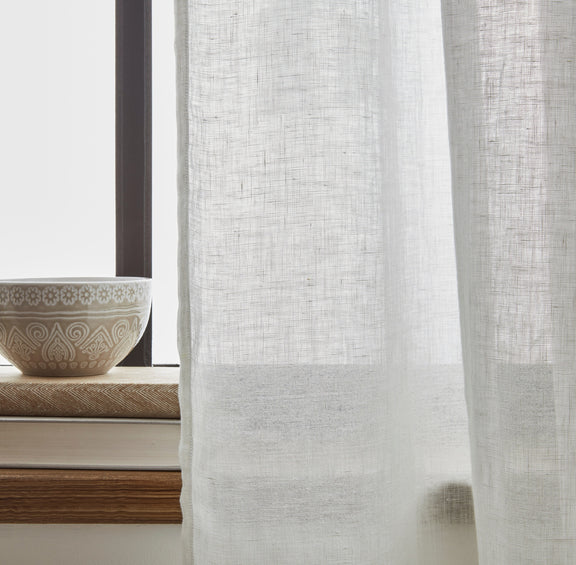 Sheer white curtain with a decorative bowl on a windowsill in the background