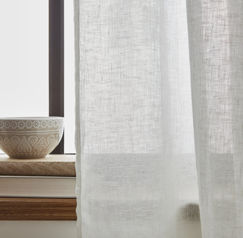 Sheer white curtain with a decorative bowl on a windowsill in the background