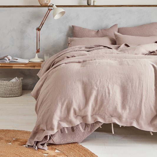 Neatly made bed with pink bedding in a bedroom setting.