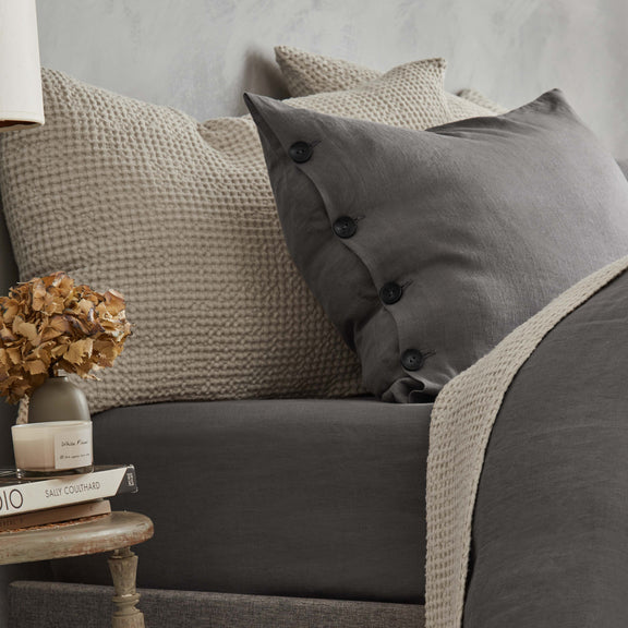 Gray sofa with textured cushions and a small table with decor items.