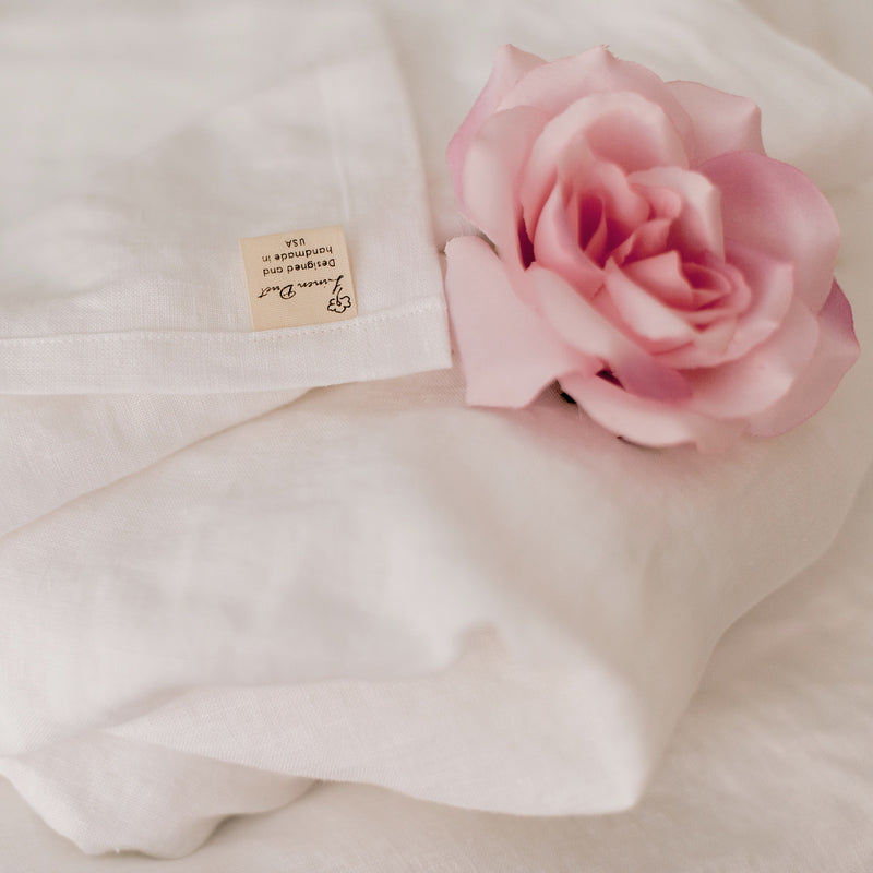 Pink rose on a white fabric background with a visible brand label.
