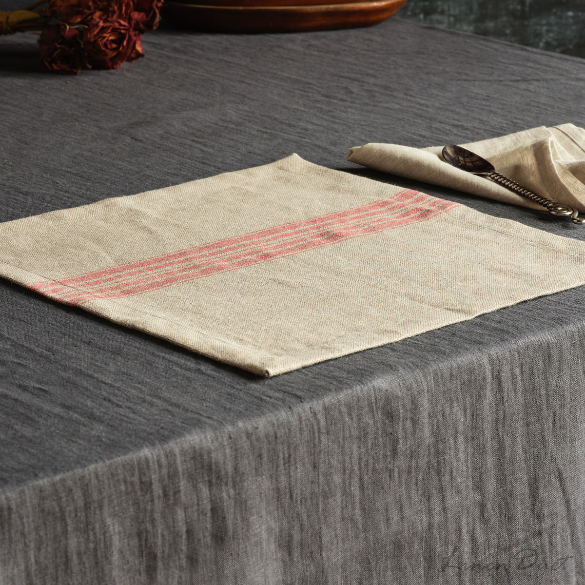Beige placemat with red stripes on a dark textured surface