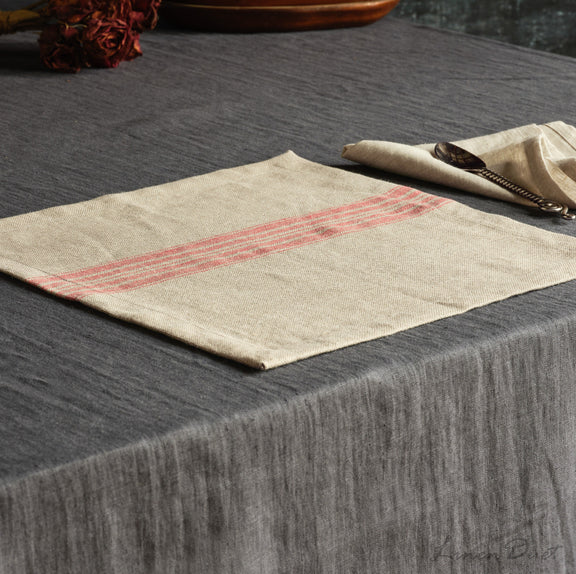 Beige placemat with red stripes on a dark textured surface
