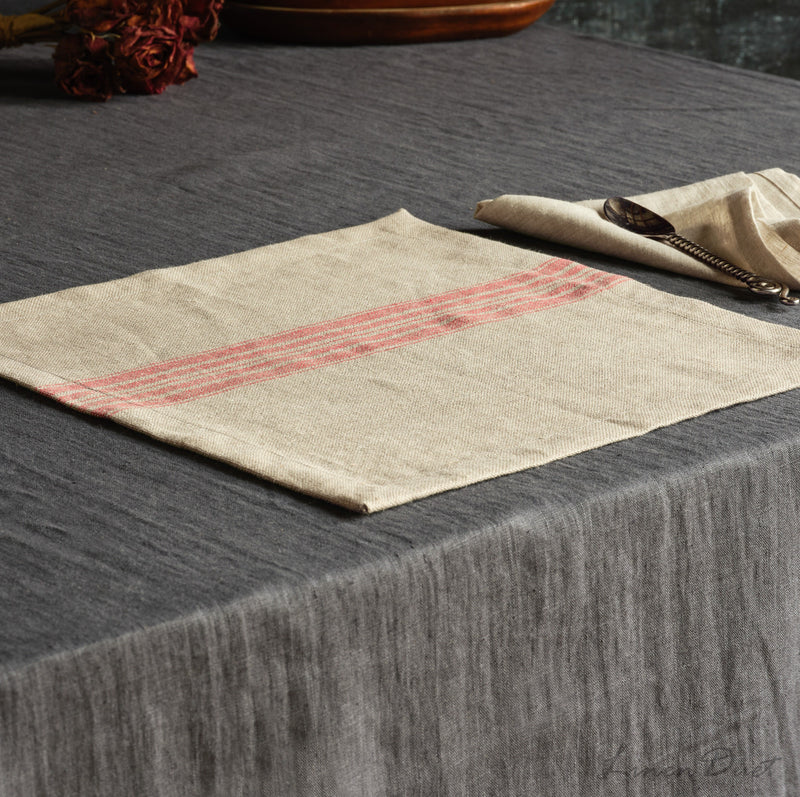 Beige placemat with red stripes on a dark textured surface