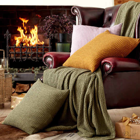 Cozy living room with a fireplace, brown leather sofa, and green and yellow cushions.
