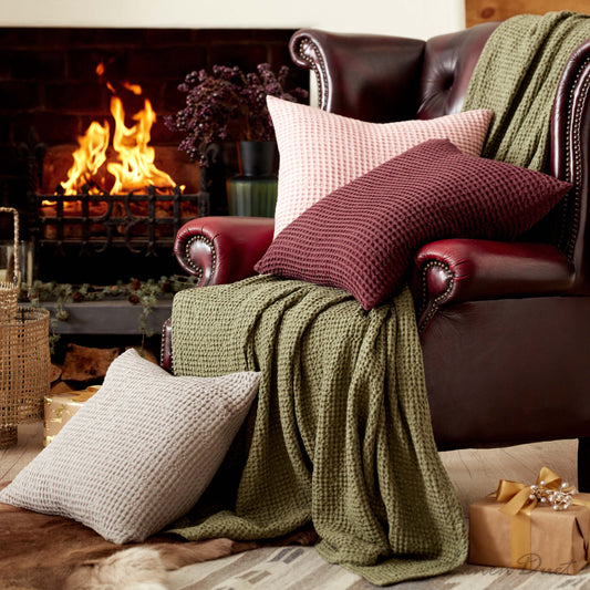 Cozy living room with a fireplace, brown leather sofa with pillows, and a green blanket.