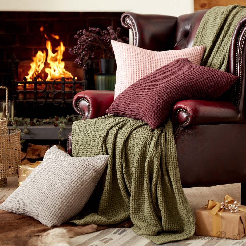 Cozy living room with a fireplace, brown leather sofa with pillows, and a green blanket.