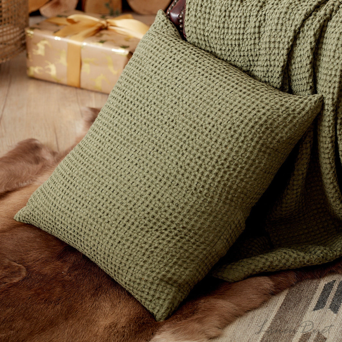 Green textured pillow on a brown surface with wrapped gifts in the background