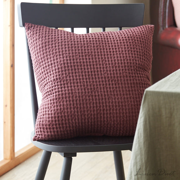 Textured red pillow on a black chair with a blurred background