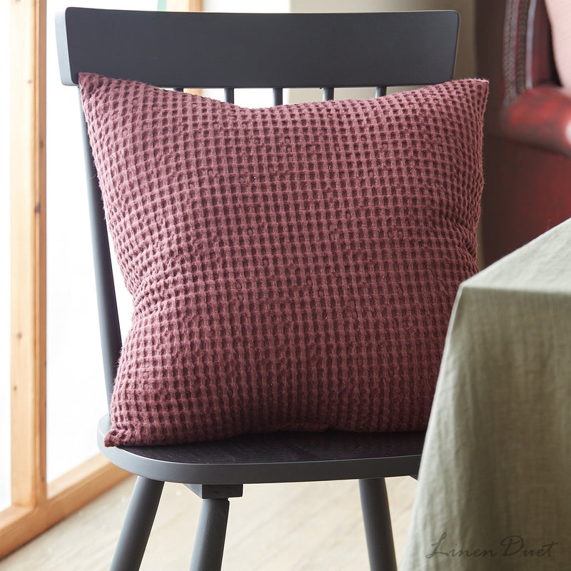 Textured red pillow on a black chair with a blurred background