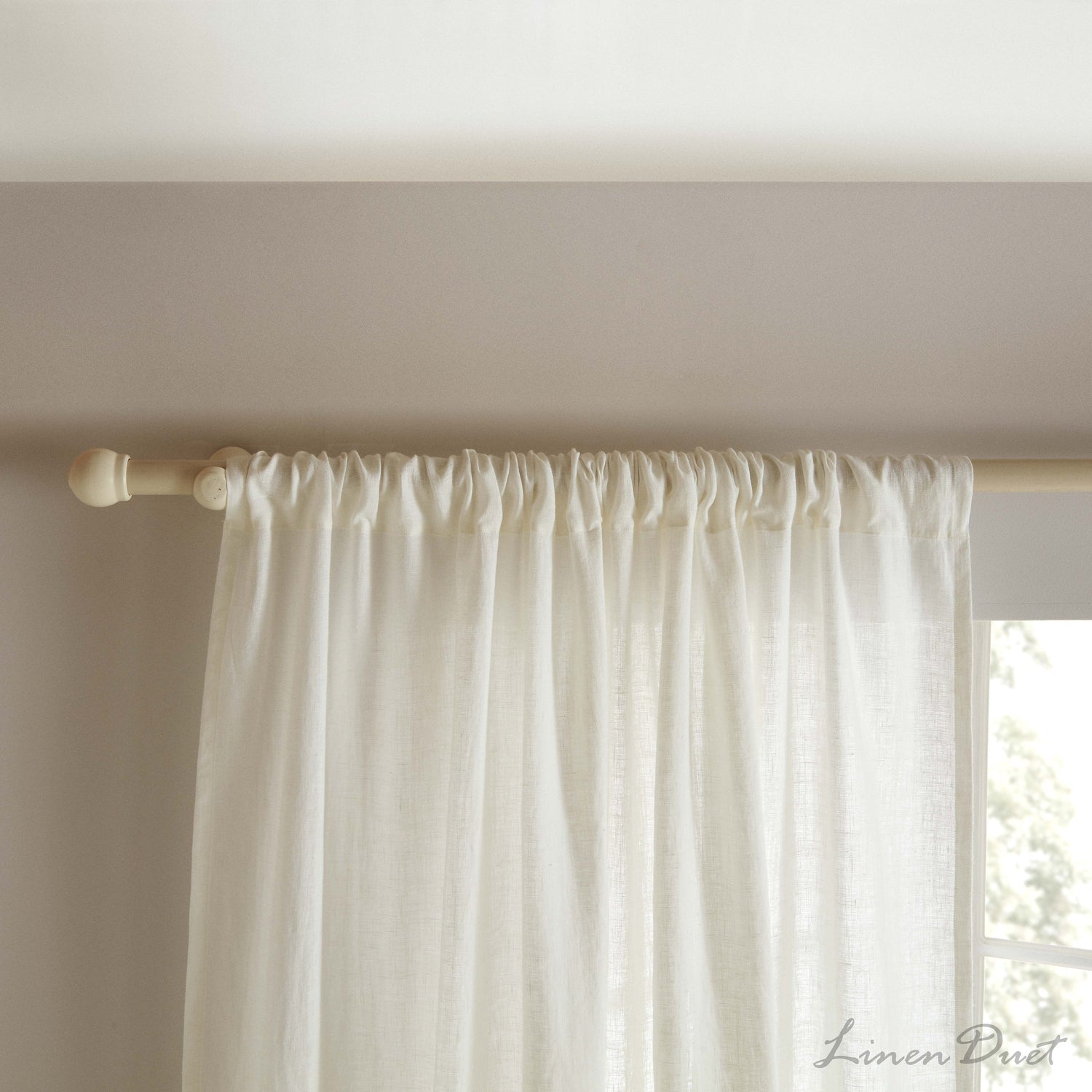 White curtain hanging from a rod against a neutral wall with 'LinenDust' branding.