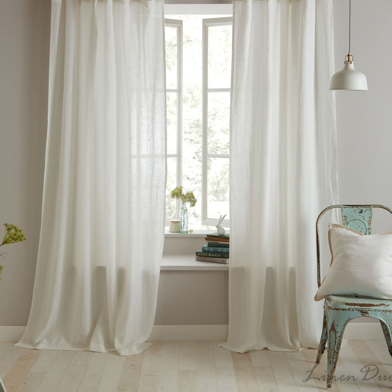 White curtains in a room with a chair and decor elements.