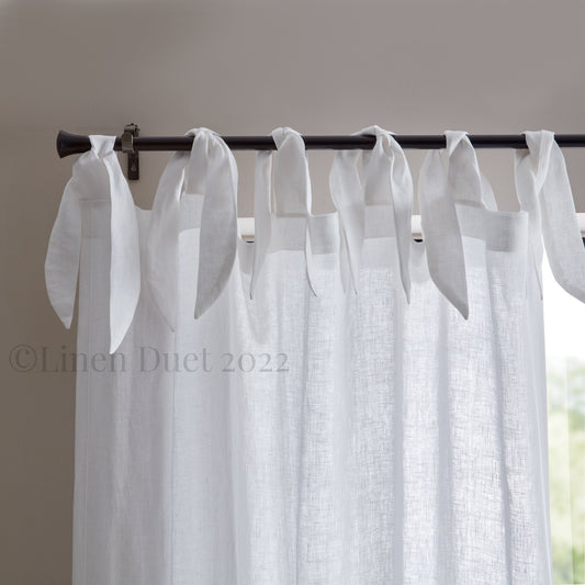 White linen curtains with a black rod against a neutral background
