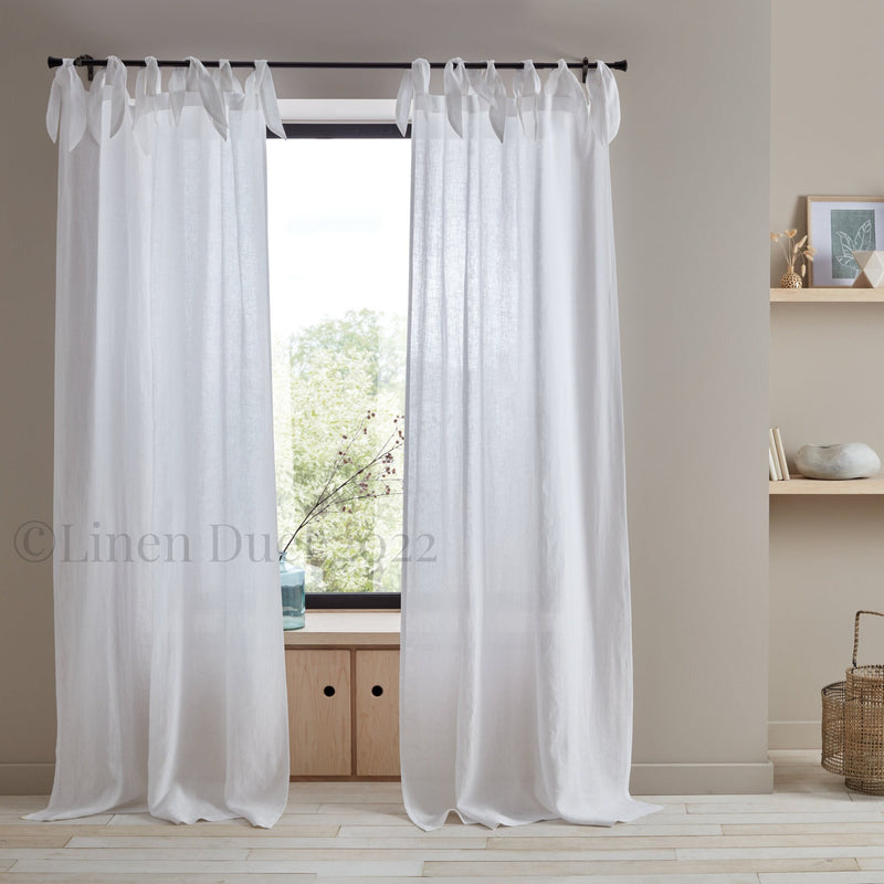 White curtains hanging in a room with a neutral color scheme.