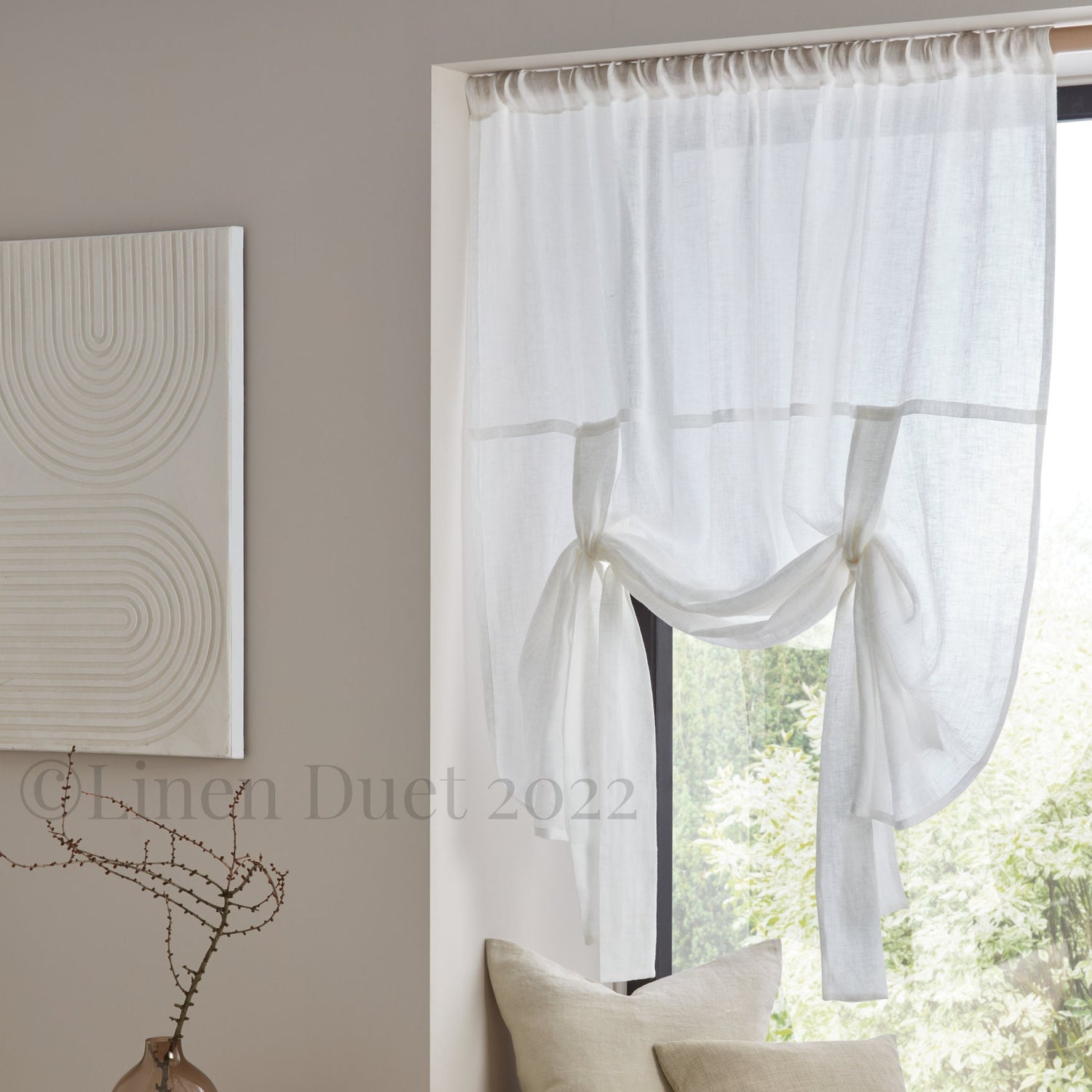Sheer white curtain with a subtle pattern in a room with a painting and decorative vase.