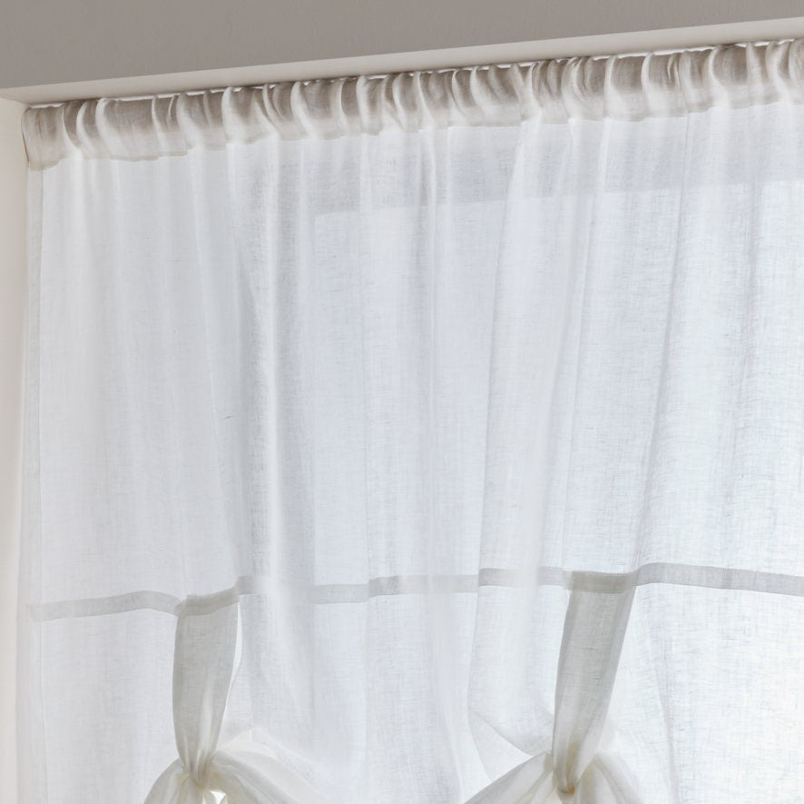 Sheer white curtain with a wooden rod on a neutral background