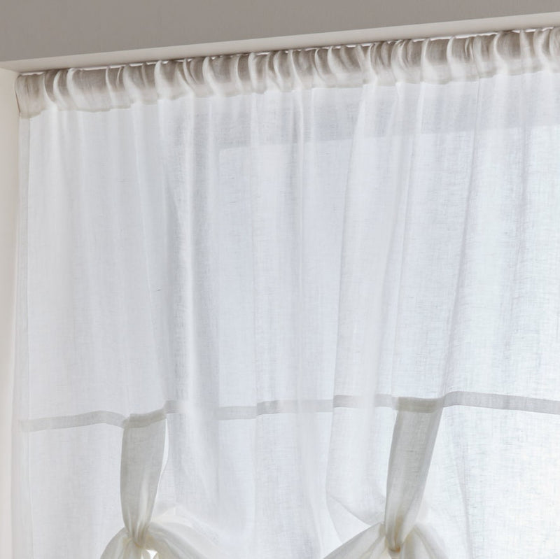 Sheer white curtain with a wooden rod on a neutral background