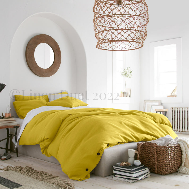 Modern bedroom with yellow bedding and a wicker lamp.