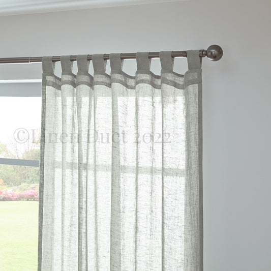 Sheer curtain with gray tab top on a rod against a white wall.